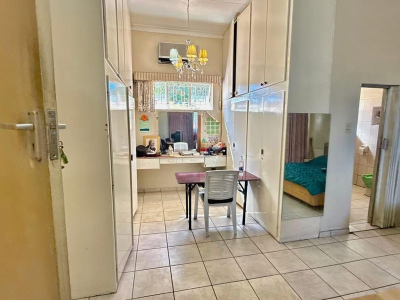 Bedroom featuring extensive built-in cupboard storage, tiled flooring, and an integrated air conditioning unit with direct access to an en-suite bathroom.