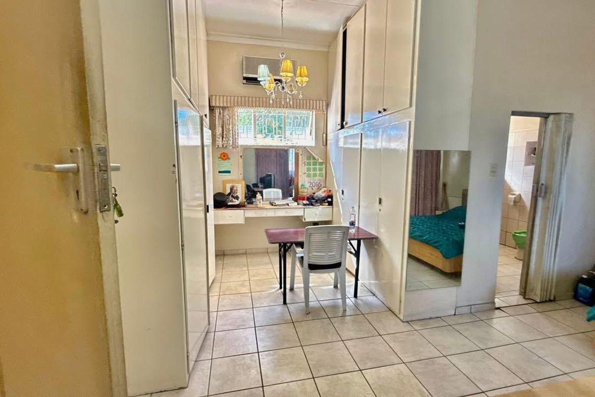 Bedroom featuring extensive built-in cupboard storage, tiled flooring, and an integrated air conditioning unit with direct access to an en-suite bathroom.