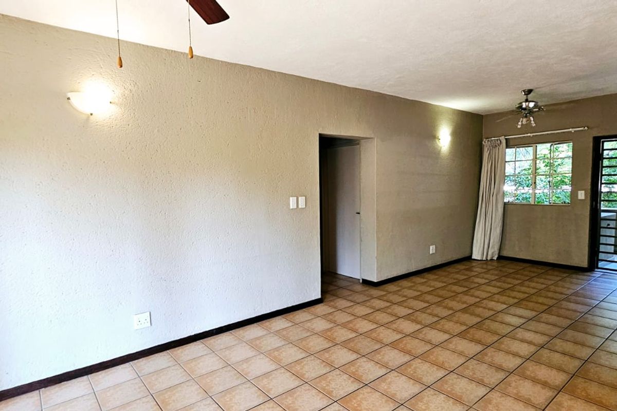 Spacious living area featuring neutral textured walls, ceramic floor tiles, built-in shelving, and ceiling fans, offering a versatile layout for comfortable living.