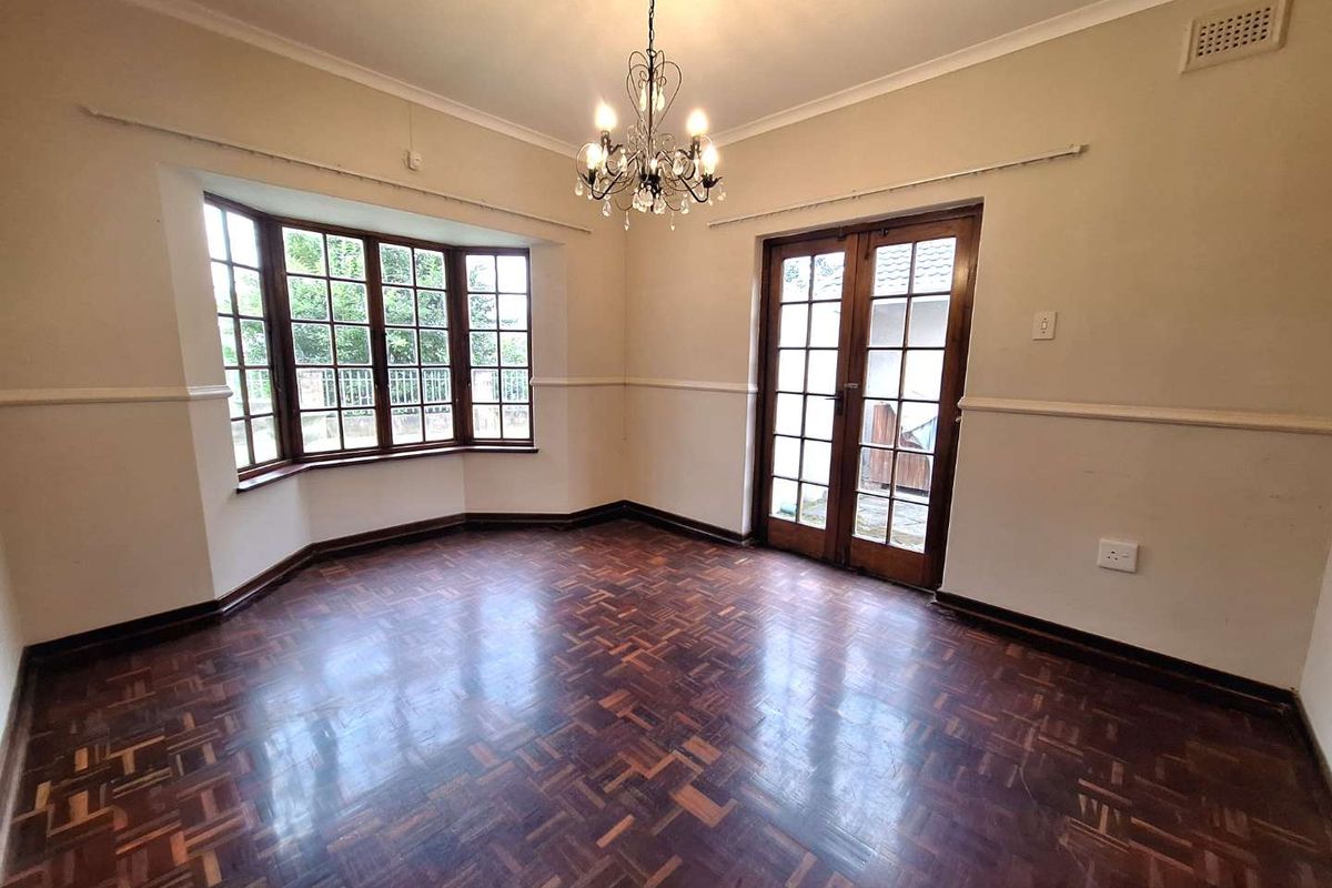 Spacious living room featuring classic parquet flooring, a charming bay window, and elegant french doors leading to the exterior.