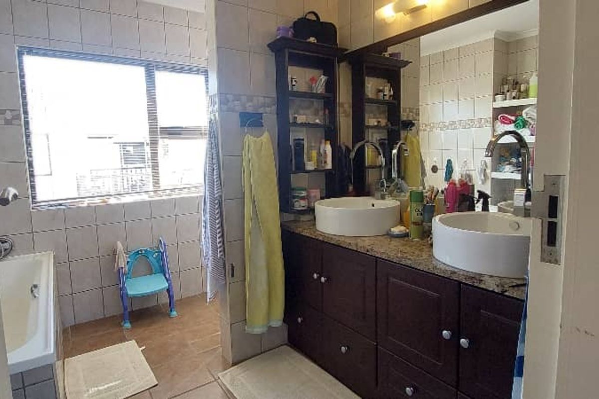A functional bathroom featuring a double vanity with vessel sinks, a bathtub, and tiled walls, offering a practical layout with natural light.