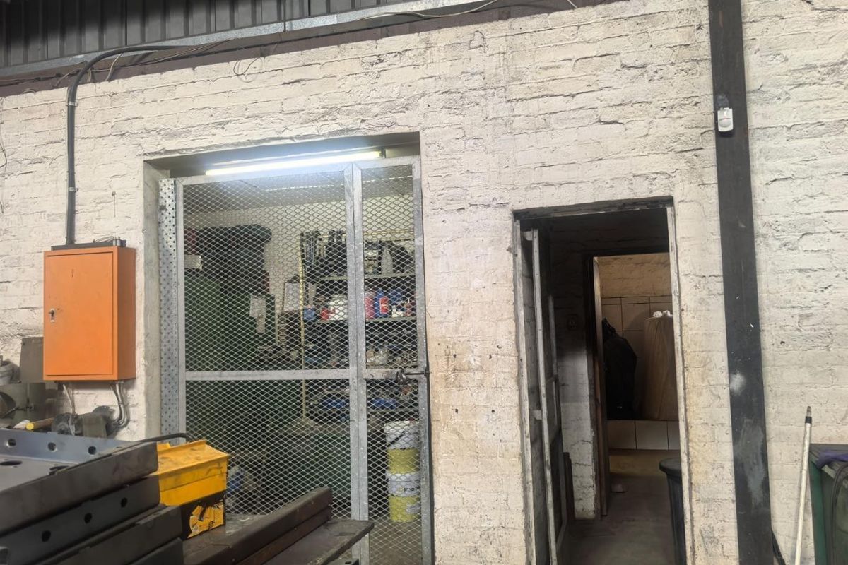 Industrial utility space featuring exposed brick walls, a metal security gate, and an integrated electrical distribution board.