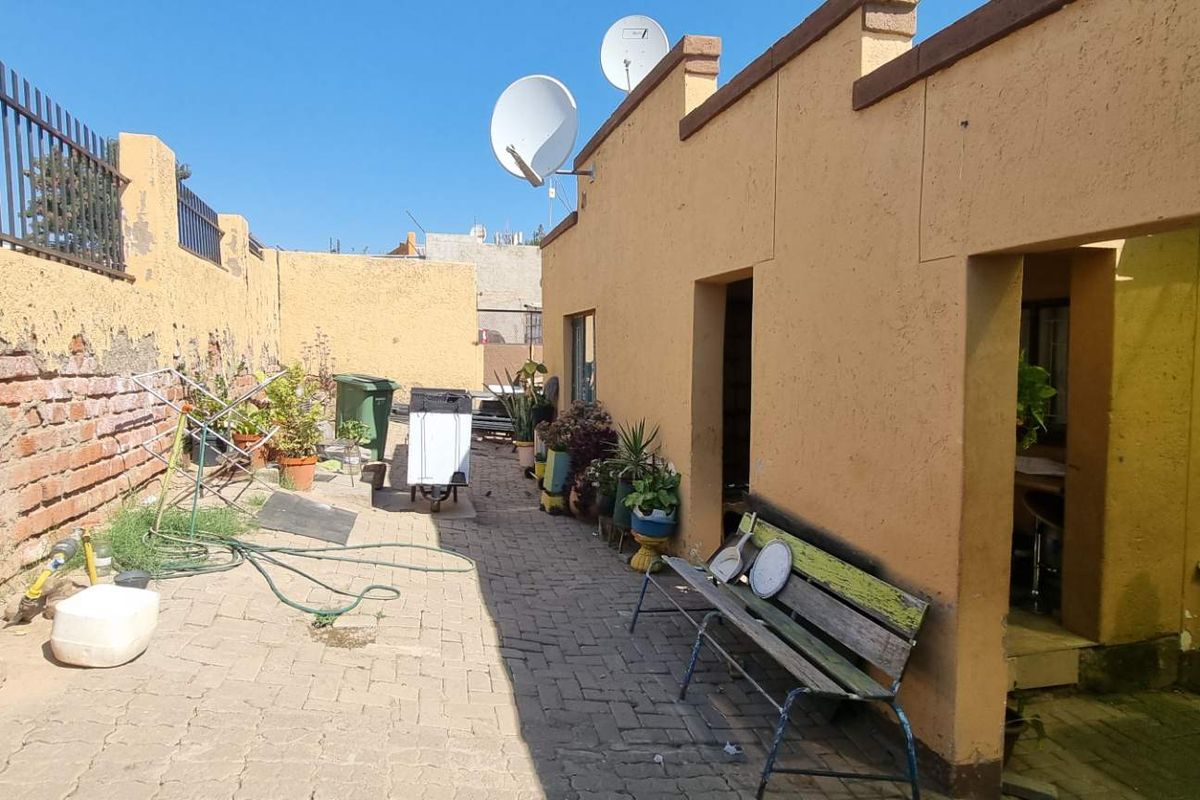 A paved rear courtyard area featuring a boundary wall with exposed brickwork and weathered plaster finishes.