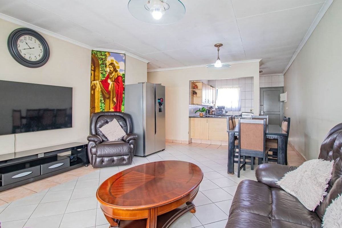 Open plan living and dining area featuring tiled flooring and a functional kitchen with built-in cabinetry.