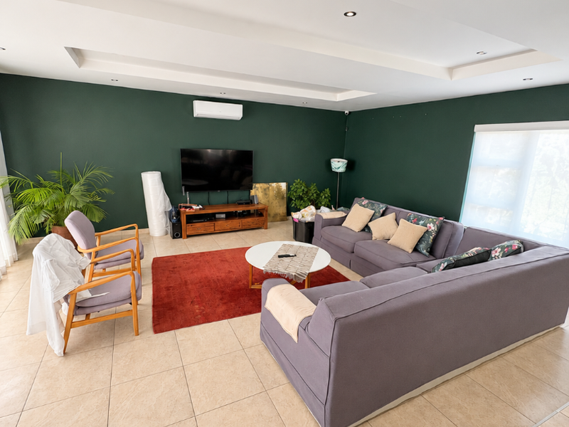 Spacious living room featuring a modern recessed ceiling with downlights, tiled flooring, and a wall-mounted split-system air conditioner.