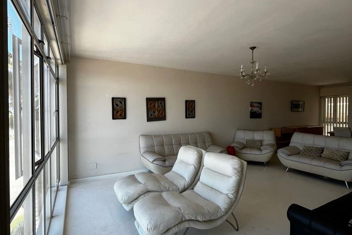 Spacious living area featuring large floor-to-ceiling windows that provide ample natural light and a bright, open atmosphere.