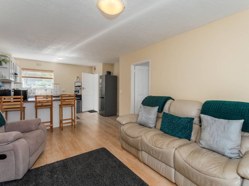 Open plan living area featuring a functional kitchen with cabinetry and laminate flooring, seamlessly connecting to the lounge space.