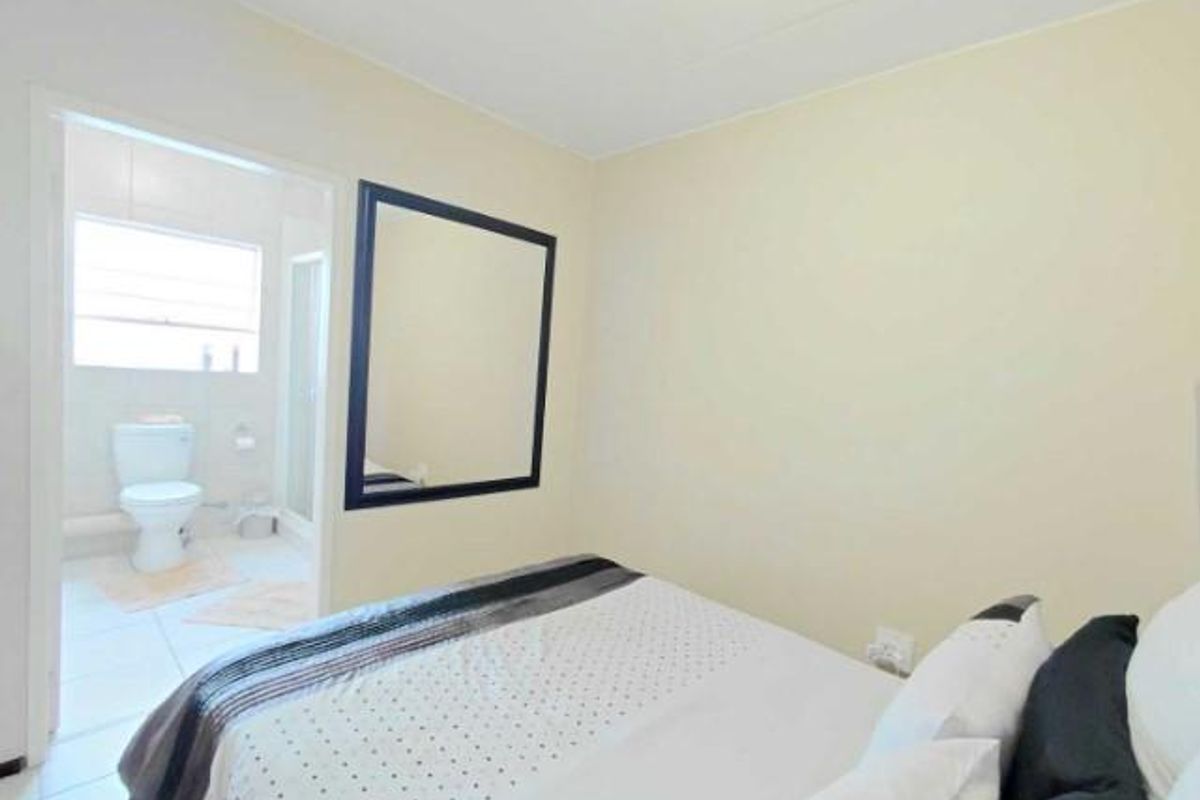A bedroom featuring neutral walls and an en-suite bathroom with a toilet and shower enclosure.
