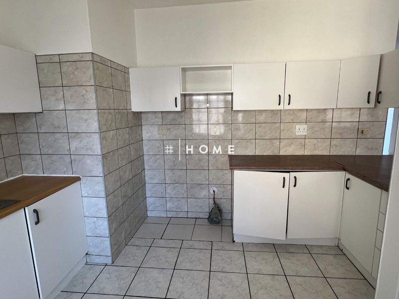 A functional kitchen space featuring tiled walls and flooring, laminate countertops, and white built-in cabinetry, ready for a modern update.