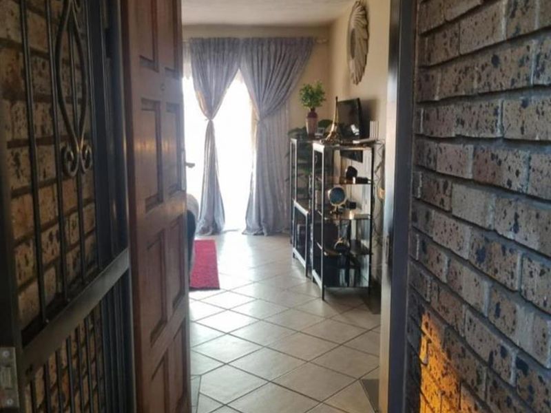 Entrance area featuring a security gate, timber door, and tiled flooring leading into the main living space.