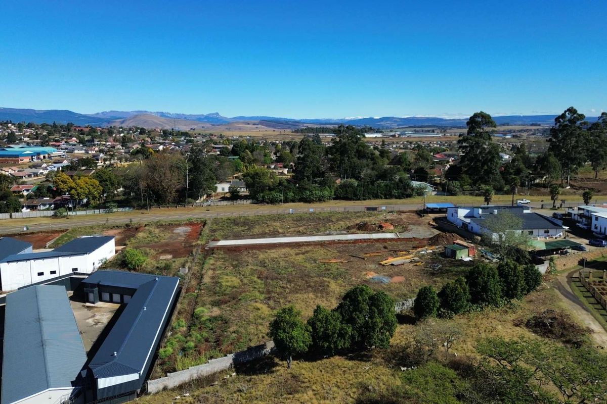 Aerial view of a vacant commercial land plot featuring a concrete foundation slab, surrounding boundary walls, and adjacent commercial buildings in a developed area.