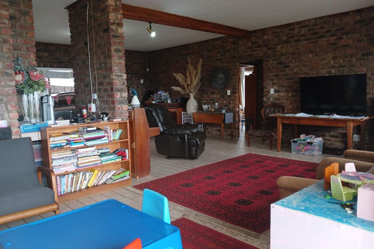Spacious living area featuring exposed face-brick walls, tiled flooring, and a prominent structural brick pillar, offering a rustic and open-plan layout.
