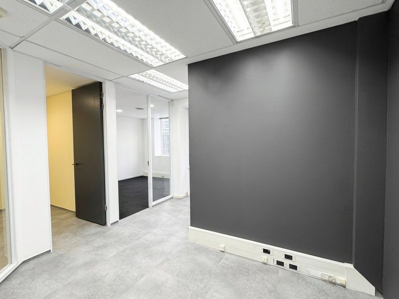 A modern, vacant office space featuring glass partitions, suspended ceilings with recessed lighting, and integrated skirting trunking for power and data connectivity.