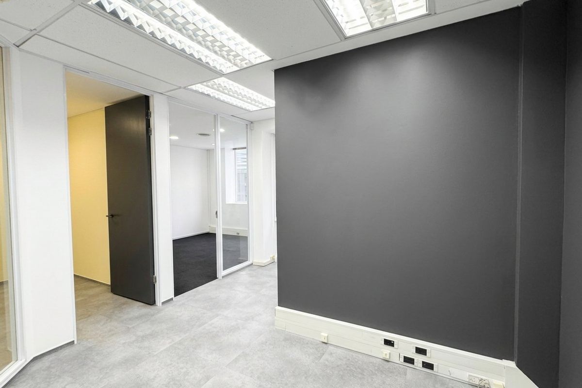 A modern, vacant office space featuring glass partitions, suspended ceilings with recessed lighting, and integrated skirting trunking for power and data connectivity.
