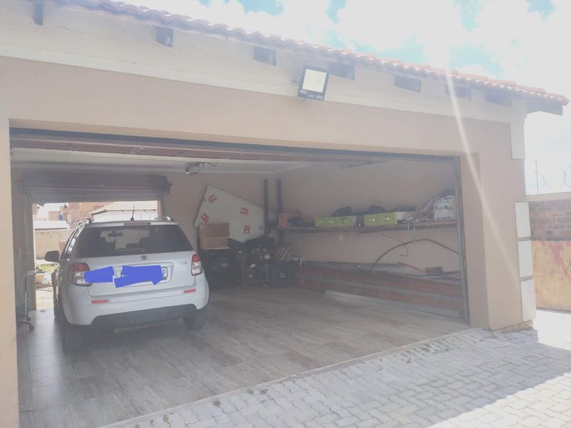 A functional garage space featuring tiled flooring and built-in shelving, providing convenient storage and vehicle parking.