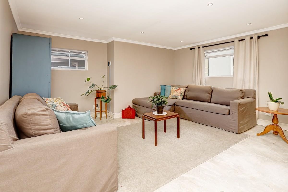 A well-lit living room featuring neutral wall tones, tiled flooring, and recessed downlighting, providing a comfortable and versatile space for relaxation.