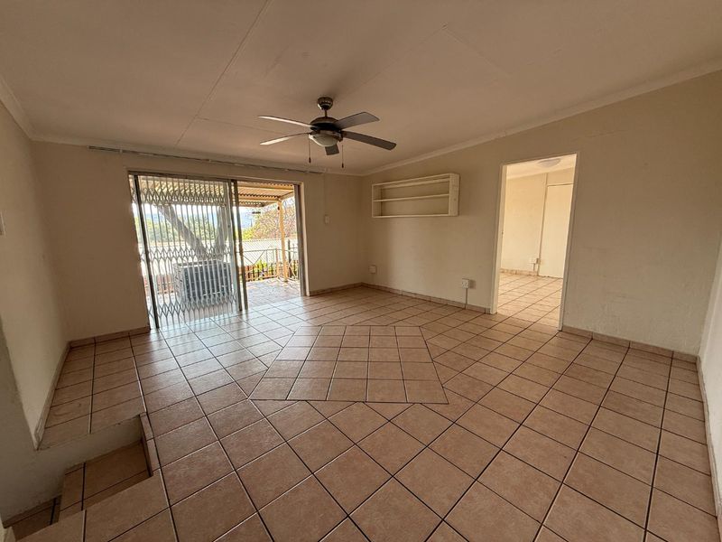 Spacious living area featuring tiled flooring, a ceiling fan, and sliding door access to an outdoor patio space.