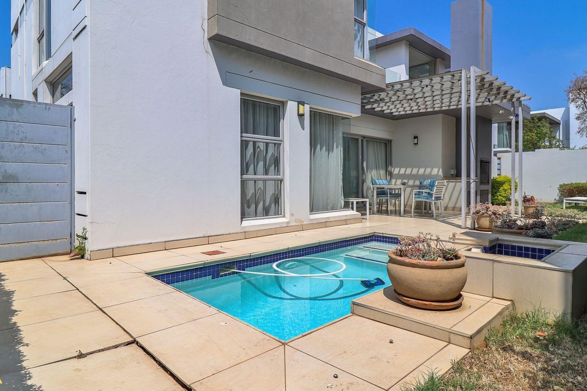 Rear exterior view featuring a private swimming pool, a covered patio area with a built-in braai, and a small garden space.