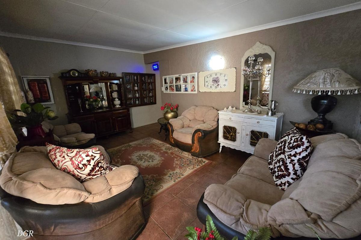 A spacious living room featuring tiled flooring and neutral wall finishes, providing a comfortable and traditional seating area.