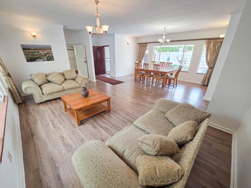 Spacious open-plan living and dining area featuring modern laminate flooring, neutral walls, and ample natural light through large windows.