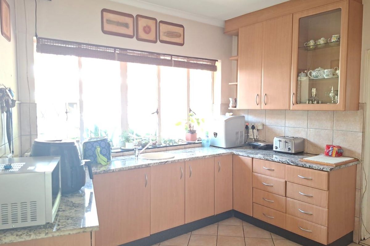 A functional kitchen featuring light wood-finish cabinetry, granite countertops, and tiled backsplash, offering a practical layout with ample storage space.