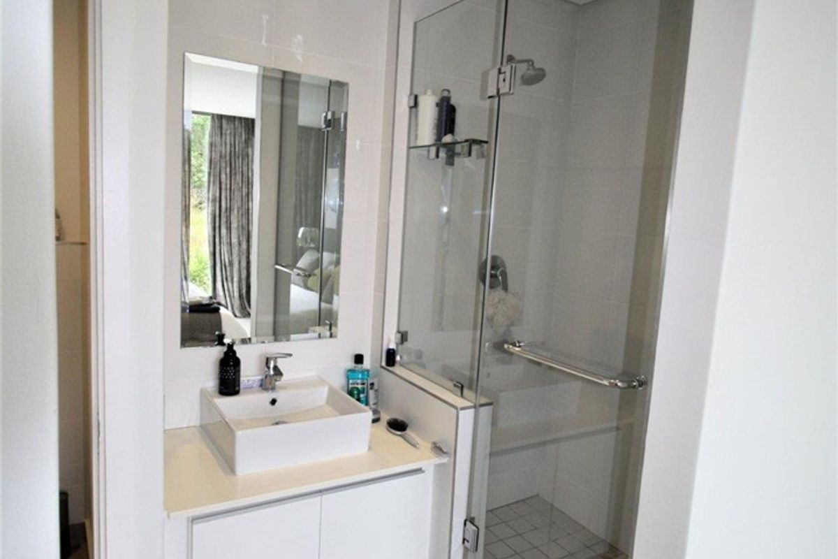 Modern bathroom featuring a vessel sink with vanity cabinet, glass-enclosed shower, and neutral tiled flooring.