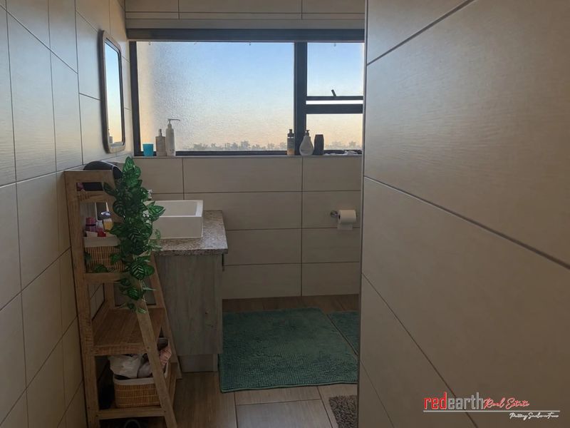 A modern bathroom featuring tiled walls, a vanity cabinet with a vessel sink, and a window providing natural light.