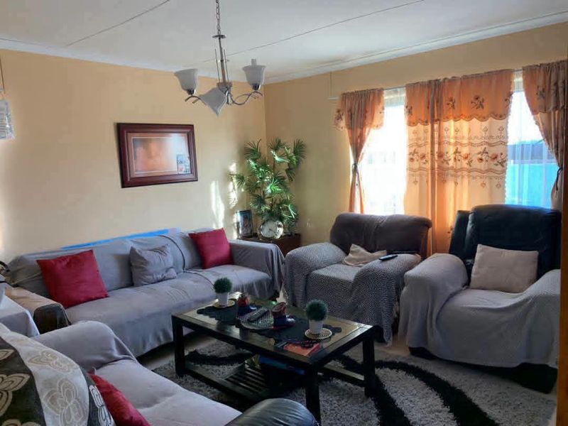A comfortable living room featuring neutral wall tones, natural light through window treatments, and a central ceiling light fixture.