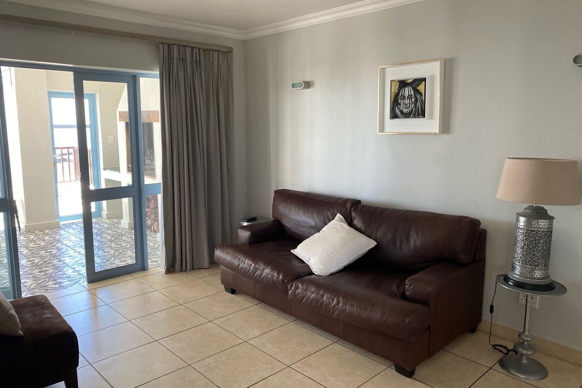 A comfortable living room featuring tiled flooring and large glass sliding doors that open onto a covered patio area.