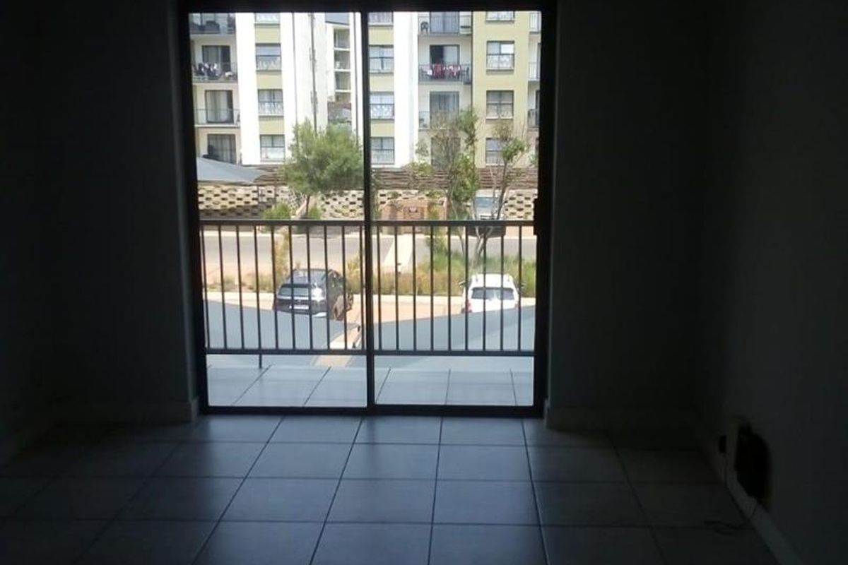 A living area featuring tiled flooring and a large sliding glass door that opens onto a balcony with exterior views.