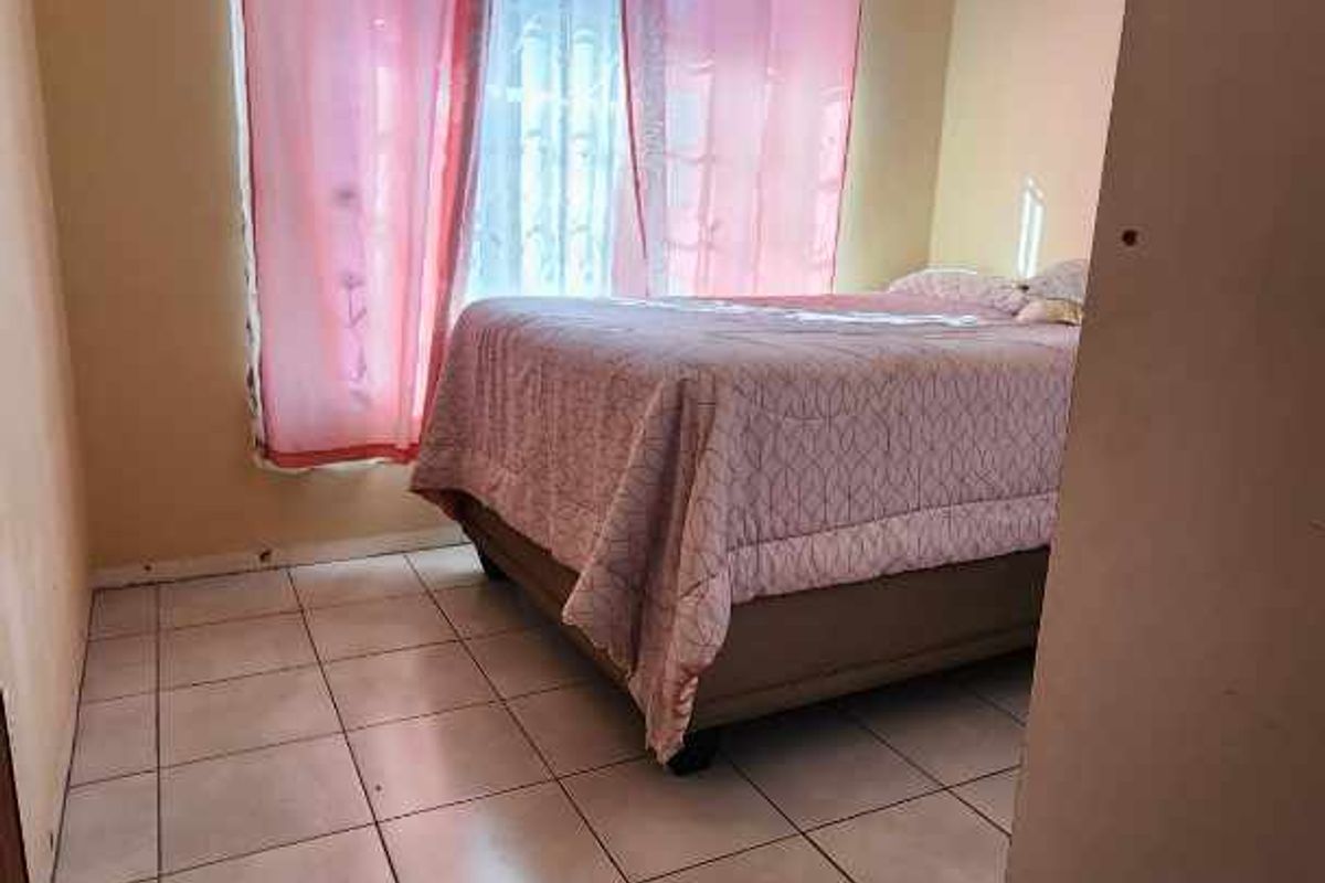 A bedroom featuring tiled flooring, a ceiling fan, and a window with natural light.