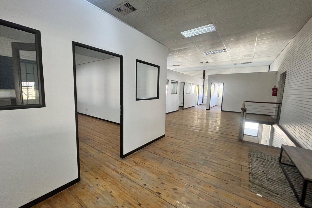Spacious open-plan office area featuring timber flooring, suspended ceilings with recessed lighting, and multiple partitioned office rooms.