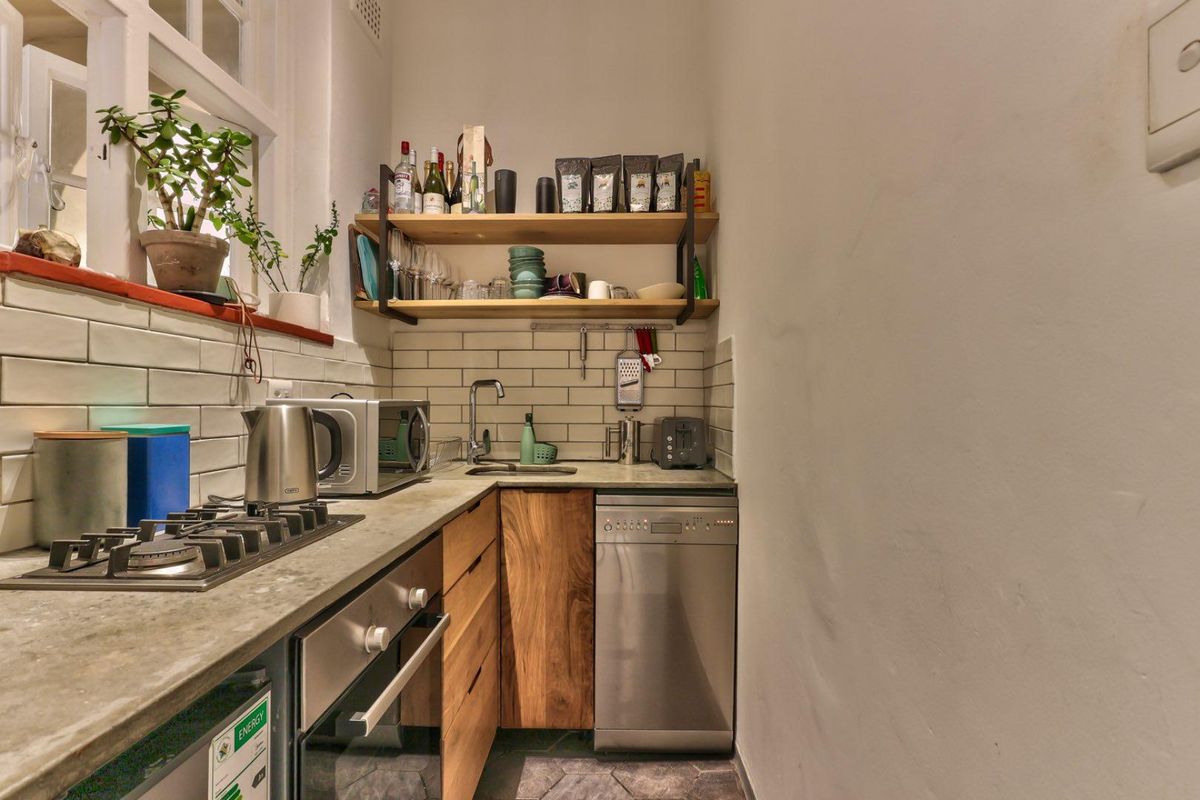 Compact kitchen featuring subway tile backsplash, wooden cabinetry, integrated oven, gas hob, and stainless steel dishwasher.