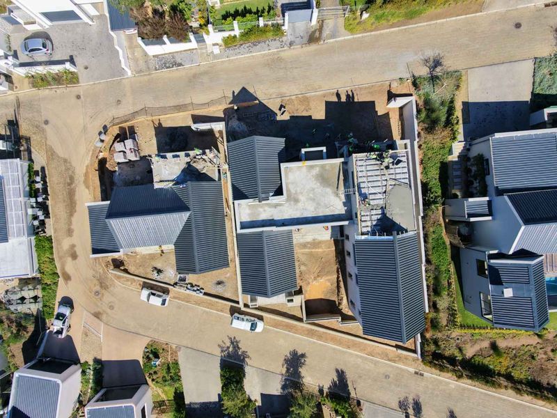 Aerial view of a residential property currently under construction, showing the roof structure, concrete slabs, and surrounding site development.
