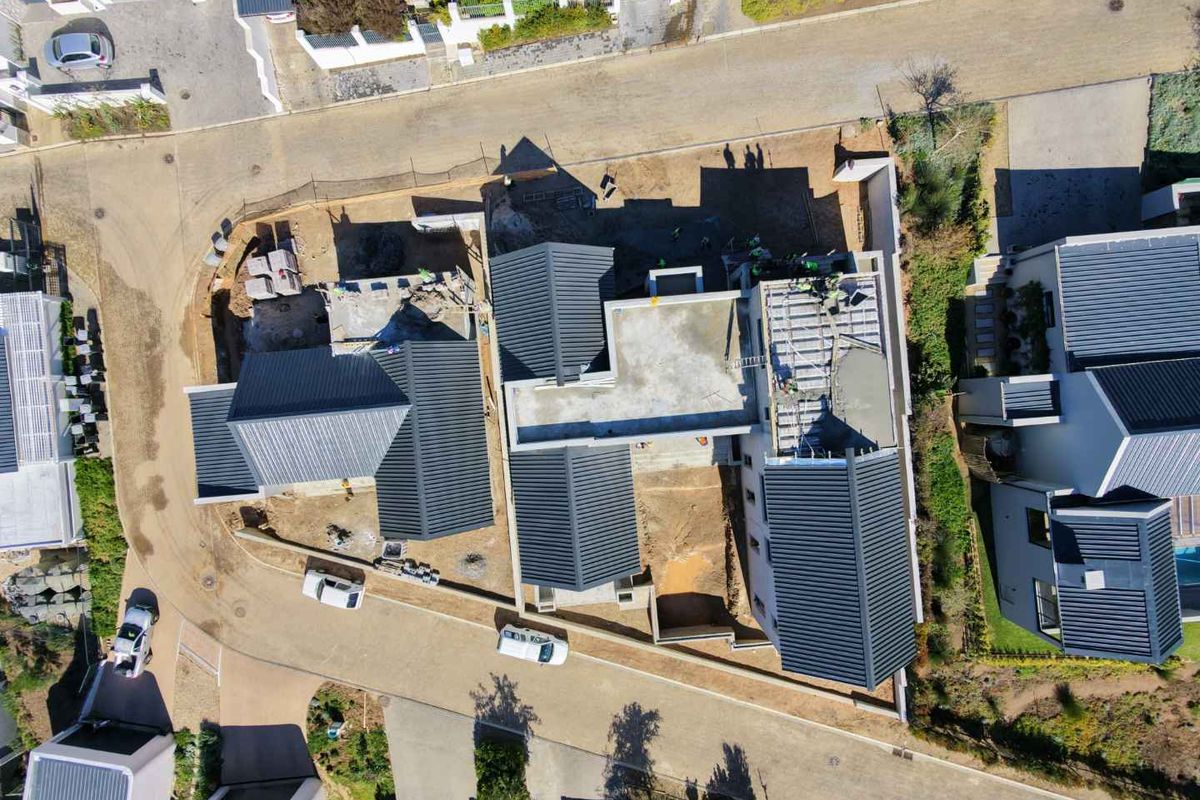 Aerial view of a residential property currently under construction, showing the roof structure, concrete slabs, and surrounding site development.