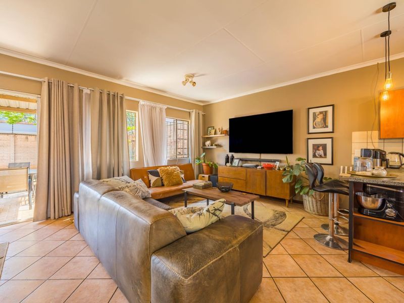 Open-plan living area featuring tiled floors, a kitchen with granite countertops, and a sliding door providing access to the outdoor patio.