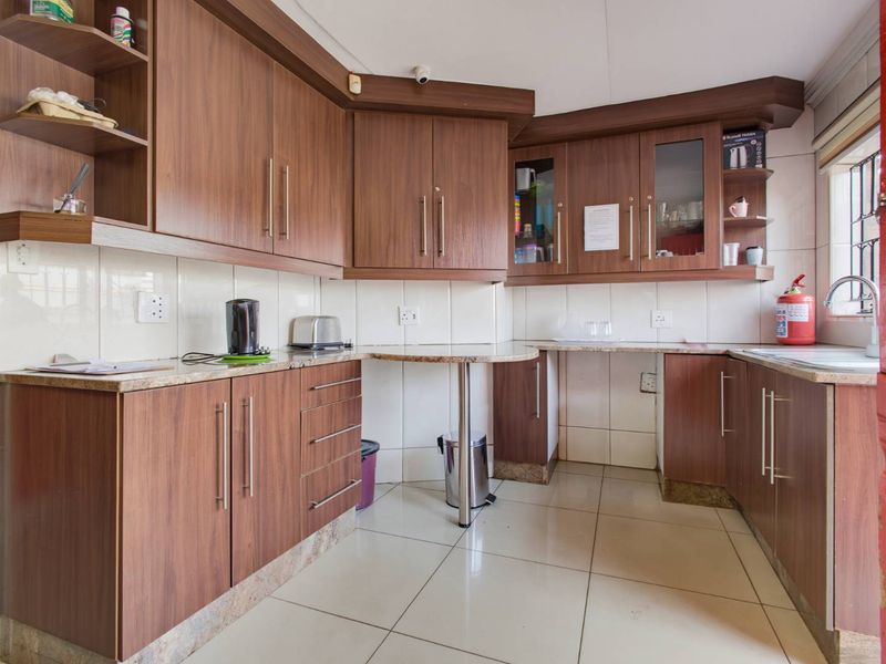 A functional kitchen featuring wood-look laminate cabinetry, granite countertops, tiled backsplash, and ceramic flooring with a practical U-shaped layout.