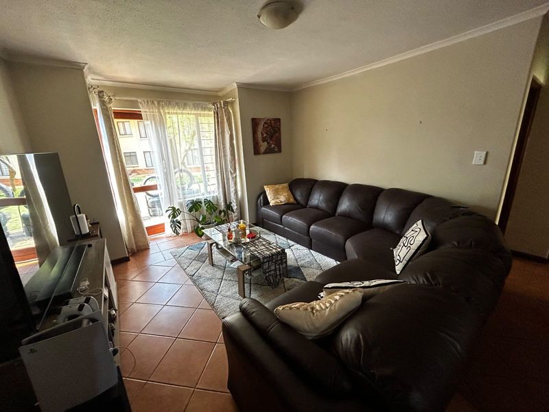 A comfortable living room featuring tiled flooring and a sliding glass door providing access to the exterior.