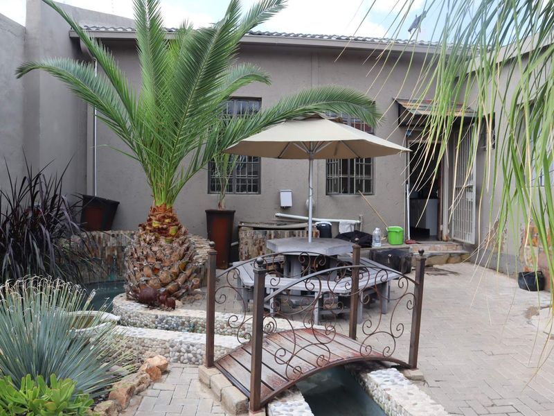 Rear courtyard area featuring paved patio, decorative water feature with a small bridge, and access to the main office building.