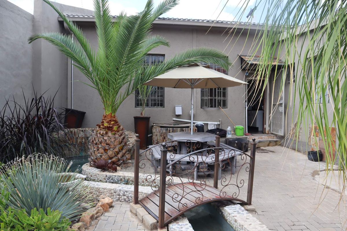 Rear courtyard area featuring paved patio, decorative water feature with a small bridge, and access to the main office building.