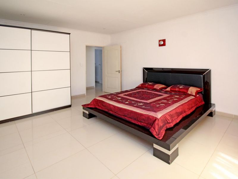 Spacious bedroom featuring large format floor tiles, built-in wardrobe, and neutral wall finishes.