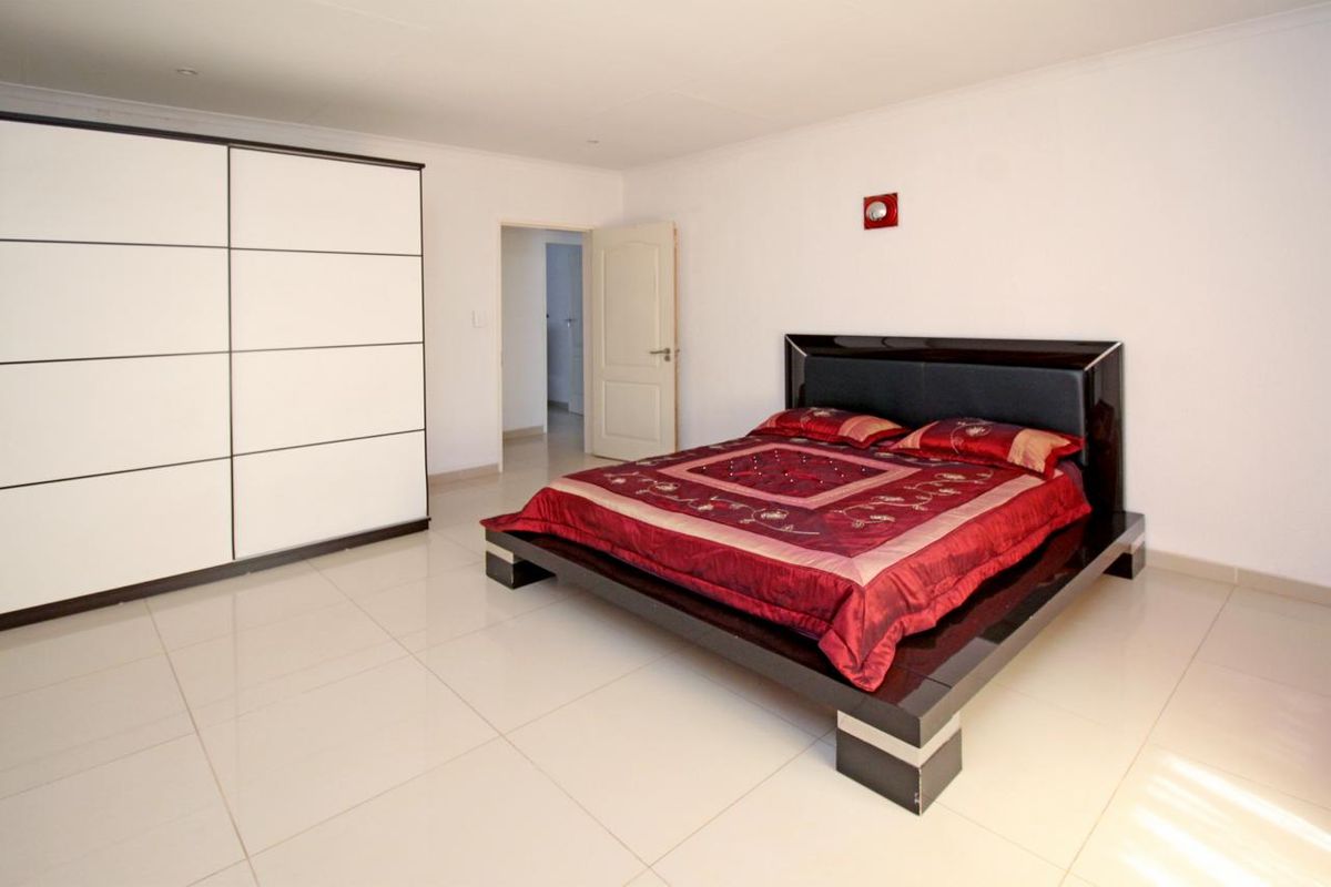 Spacious bedroom featuring large format floor tiles, built-in wardrobe, and neutral wall finishes.