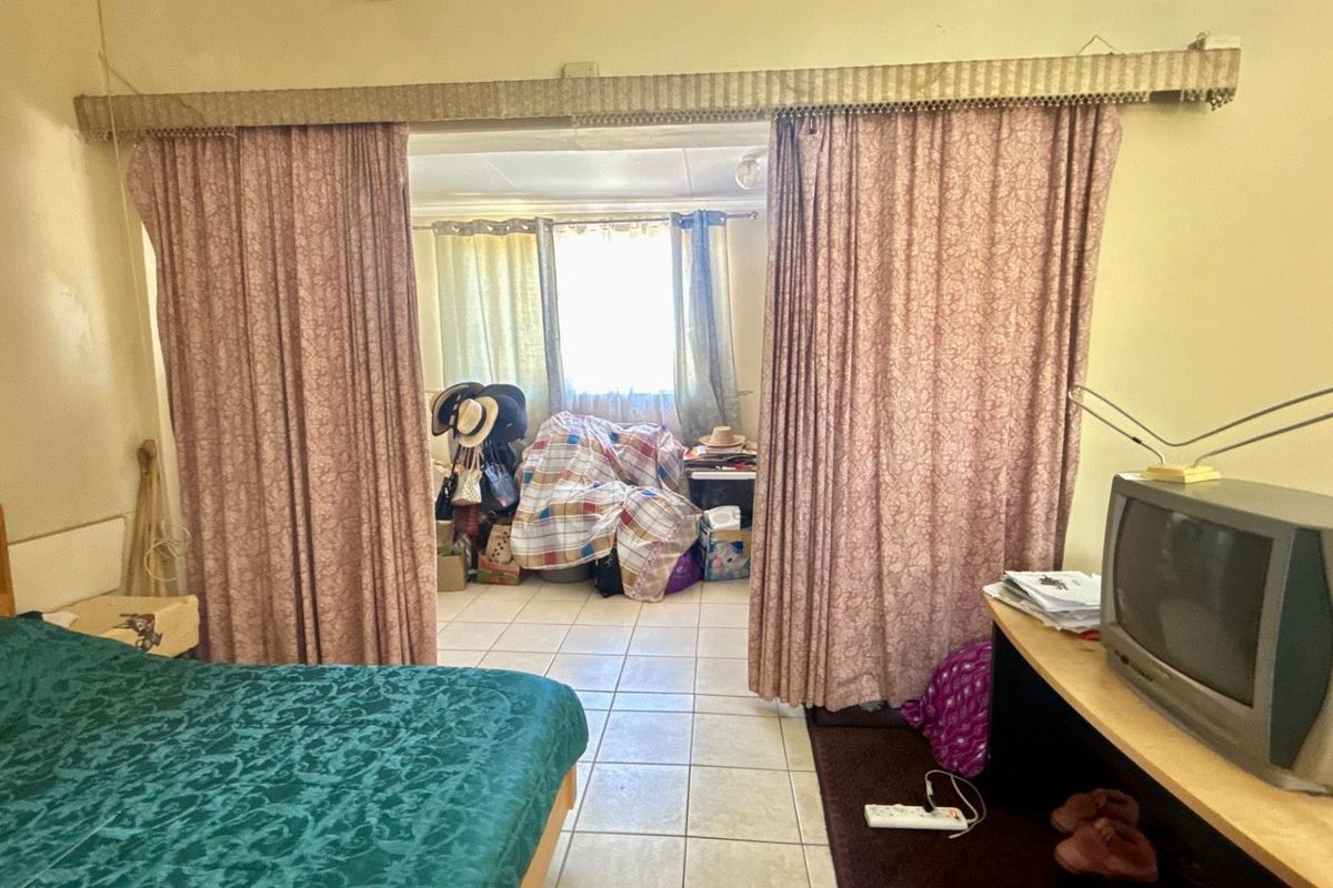 A bedroom featuring tiled flooring and a partitioned space, offering potential for modernization and improved layout configuration.