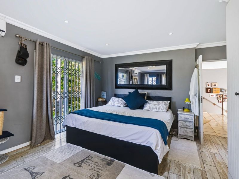 A well-maintained bedroom featuring grey walls, crown molding, recessed lighting, a split-system air conditioner, and a sliding glass door with a security gate.