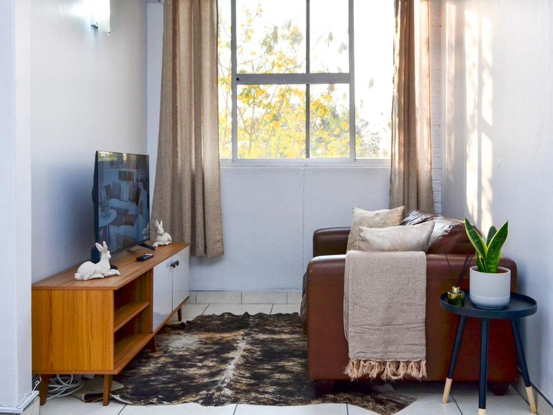 A cozy living area featuring tiled flooring and a large window that allows for natural light.