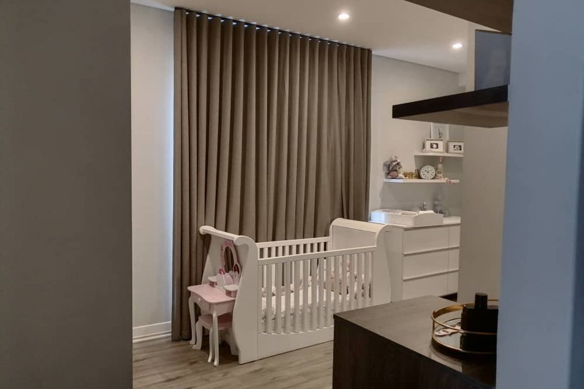 A well-maintained bedroom featuring modern laminate flooring, recessed ceiling lighting, and floor-to-ceiling curtains.
