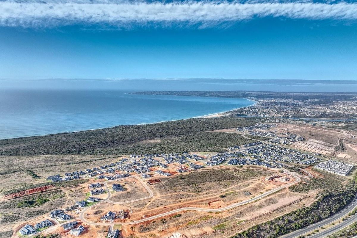 An aerial view of a residential development site featuring coastal proximity, established road infrastructure, and surrounding natural landscape.