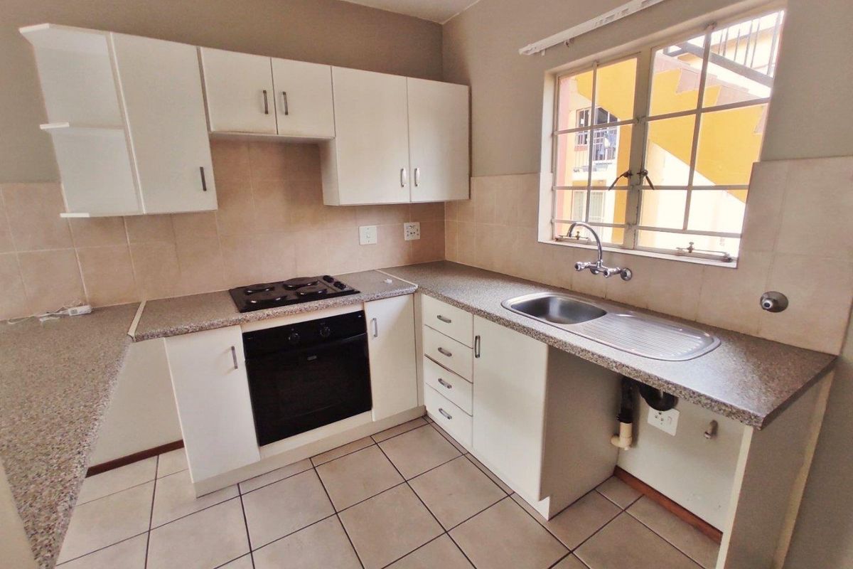 A functional kitchen featuring white built-in cabinetry, granite countertops, a built-in oven with gas hob, and tiled flooring.