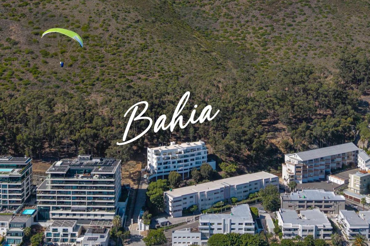 Aerial view of a residential apartment complex nestled against a mountain backdrop, showcasing the building's location and surrounding neighborhood infrastructure.