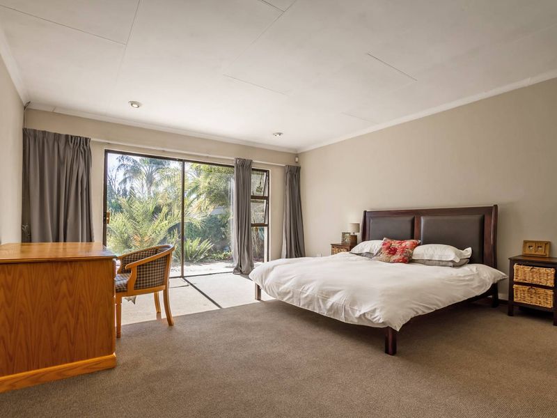 Spacious bedroom featuring neutral walls, carpeted flooring, and large sliding glass doors providing direct access to the garden.